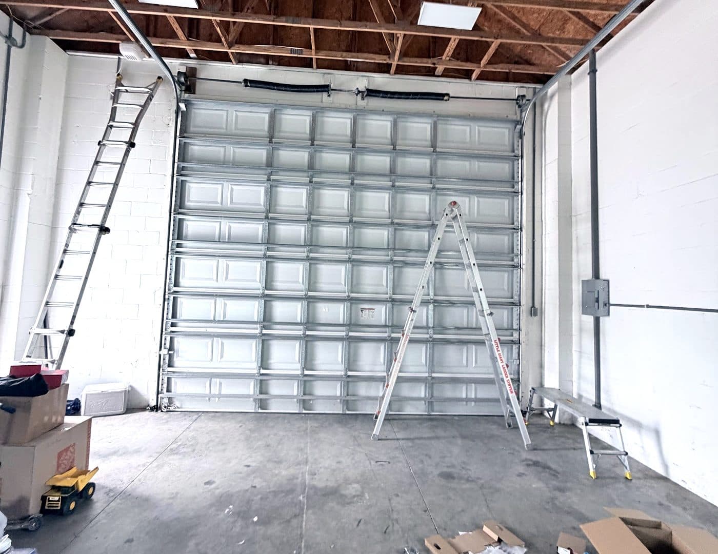 Tall commercial sectional garage door being installed in a warehouse bay